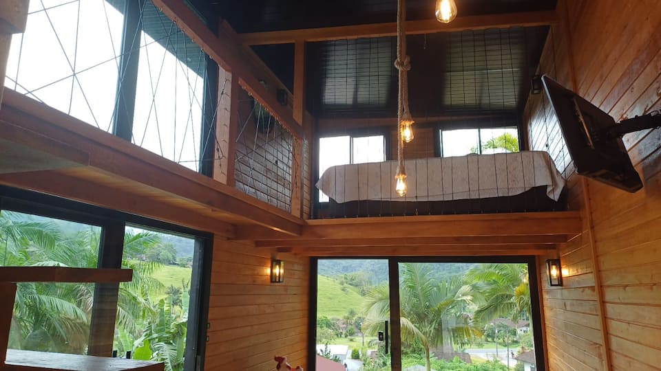 Sala da cabana com janelas panorâmicas voltadas para o verde